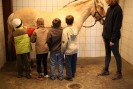 Das Foto zeigt vier Schüler beim Striegeln eines Pferdes, das von einer Therapeutin gehalten wird.