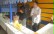 Das Foto zeigt drei Schüler am Kiosk-Stand in der Pausenhalle, von denen einer Orangensaft zum Einschenken vorbereitet. 