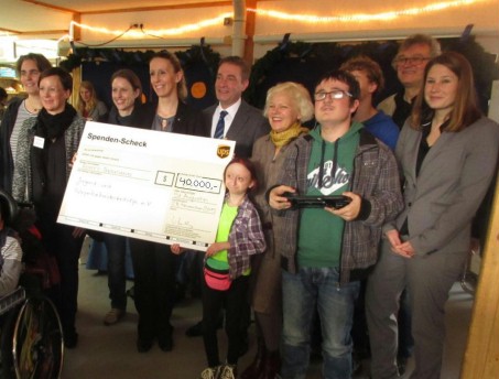 Das Foto zeigt eine Gruppe von Erwachsenen und 2 Schüler mit einem großen Scheck über 40.000 Dollar.